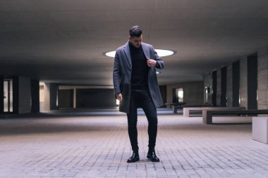 Yakışıklı genç işadamı duruyor ve paltosunu asıyor..