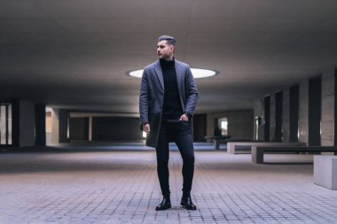 Elleri ceplerinde dizüstü bilgisayarı olan yakışıklı bir iş adamı..