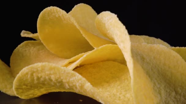Куча жареных картофельных чипсов вращается на черном фоне — стоковое видео