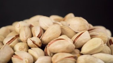 Lezzetli fıstıklar siyah arka planda izole edilmiş vaziyette dönüyorlar. Fıstık ezmesi.