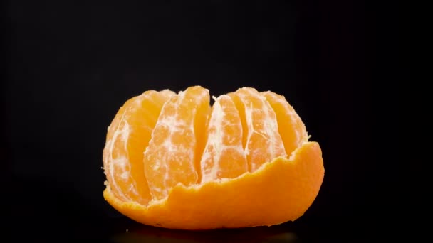 Ένα πορτοκαλί μανταρίνι εσπεριδοειδών που περιστρέφεται σε μακροεντολή. Φρούτα στο κέντρο σε ένα σκοτεινό — Αρχείο Βίντεο
