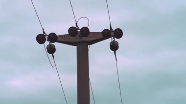 Elektrik iletimi altyapısını gösteren somut bir elektrik direğinin üst kısmının görüntüsü