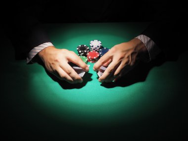 Adam yeşil arka plan üzerinde poker oynamaya.