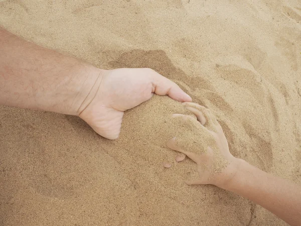 Father and son hands on sand. Close up