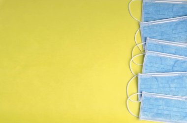 Sarı arka planda mavi tıbbi maskeler. Tıbbi konsept. Kopyalama alanı olan düz.