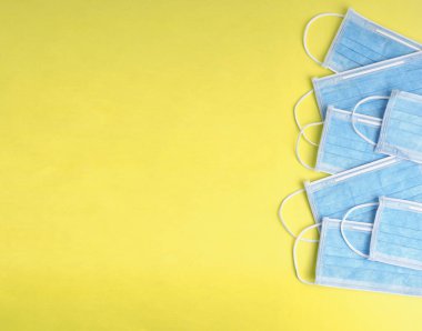 Sarı arka planda mavi tıbbi maskeler. Tıbbi konsept. Kopyalama alanı olan düz.