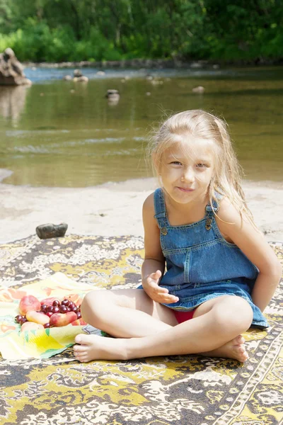 Leende flicka med picknicken på riverside — Stockfoto