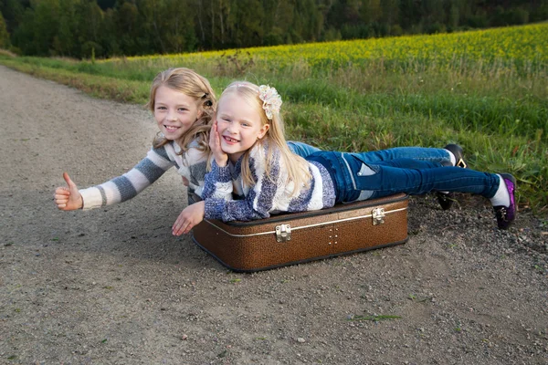 Dos chicas con la maleta de pie sobre la carretera — Foto de Stock