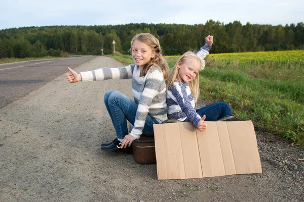 Bavul ayakta yol hakkında iki kızla — Stok fotoğraf