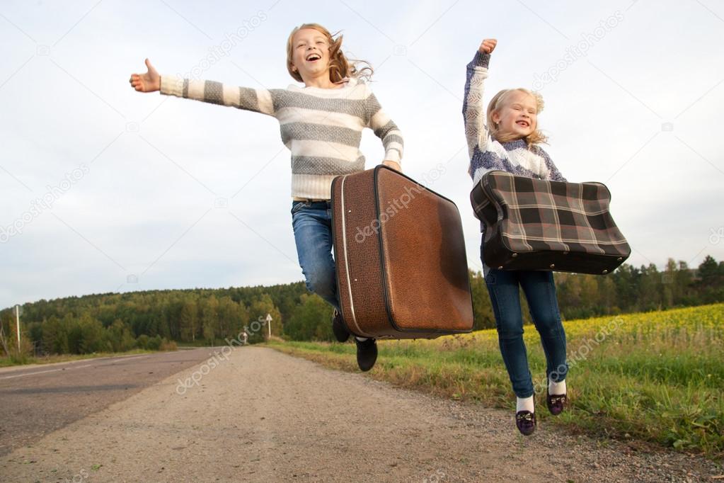 Two girls with suitcase standing about road