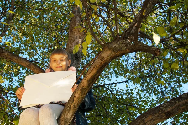 Belle fille lecture lettre tout en étant assis sur l'arbre — Photo