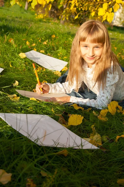 Vakker jente leser brev mens hun sitter på treet. – stockfoto