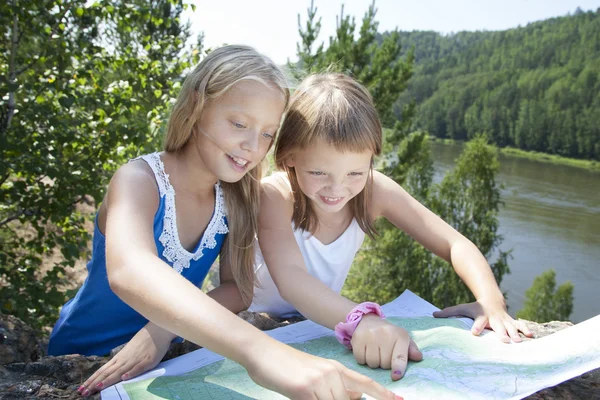 Två unga flickor i berg läsa karta nära floden — Stockfoto