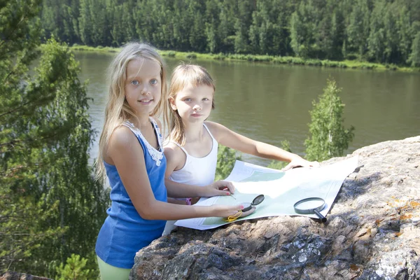 İki genç kız dağ Nehri yakınında harita okumak — Stok fotoğraf