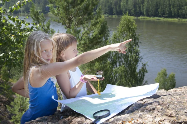 Två unga flickor i berg läsa karta nära floden — Stockfoto