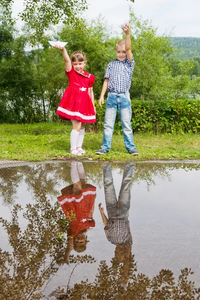 Küçük kız ve erkek kardeş kağıt tekne ile oynamak — Stok fotoğraf