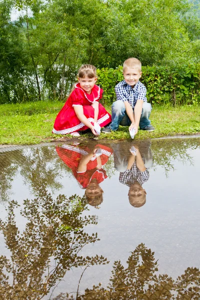 Lilla syster och bror leker med papper båtar — Stockfoto