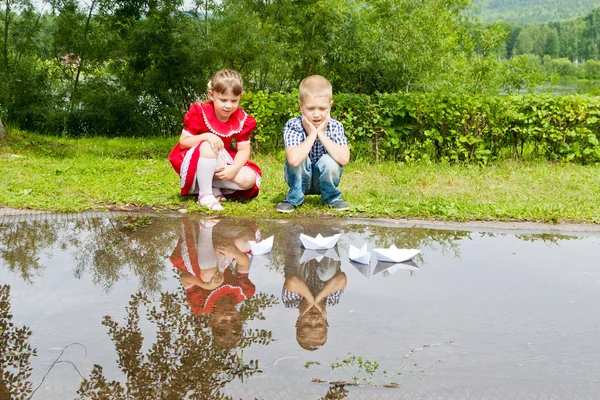 Küçük kız ve erkek kardeş kağıt tekne ile oynamak — Stok fotoğraf