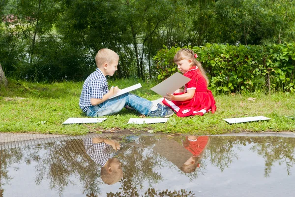 Muchacha y niño feliz escribiendo sonriendo en el jardín de verano . — Foto de Stock