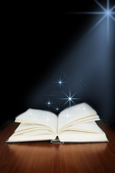 открытая книга с магическим светом на деревянных досках и темным абстрактным фоном
