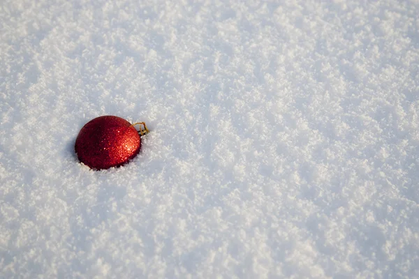 Kerstmis rode bal op besneeuwde achtergrond — Stockfoto