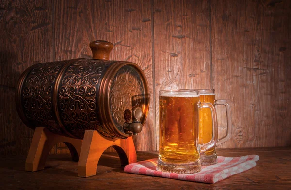 Canecas de cerveja e barril em um fundo de madeira — Fotografia de Stock