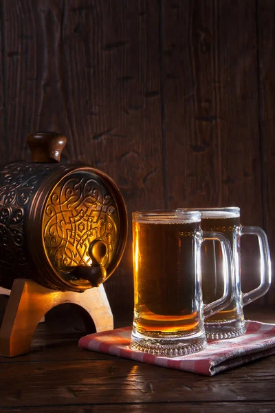 Bierkrüge und Fass auf hölzernem Hintergrund — Stockfoto