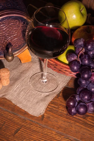 Glass of red wine and barrel on rustic wood tabel — Stock Photo, Image