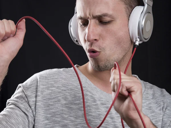 The young man enthusiastically listens to music in headphones an — Stock Photo, Image