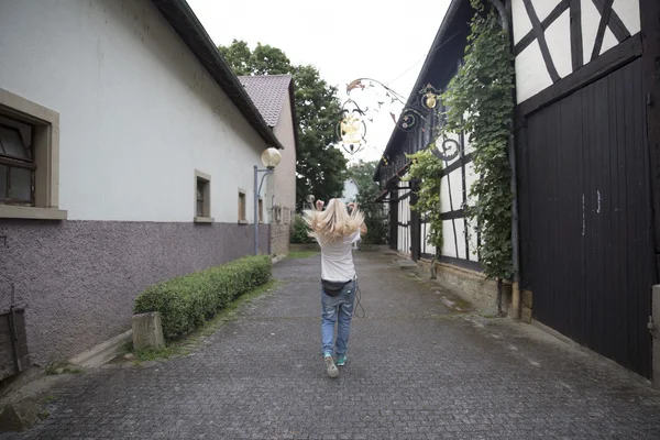 Junge blonde Frau in blauen Jeans und Hemd schreitet entlang der nar — Stockfoto