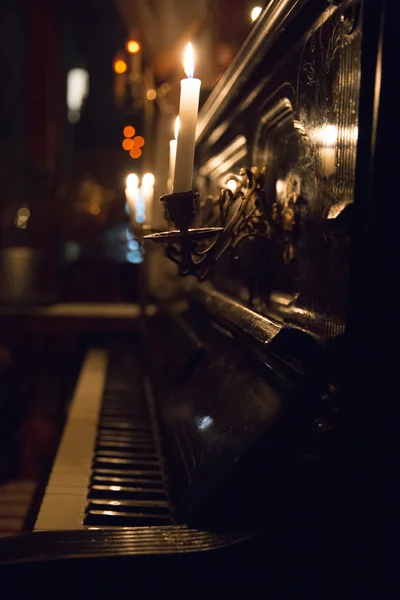 Beautiful black piano with the lid open and a burning candle in — Stock Photo, Image