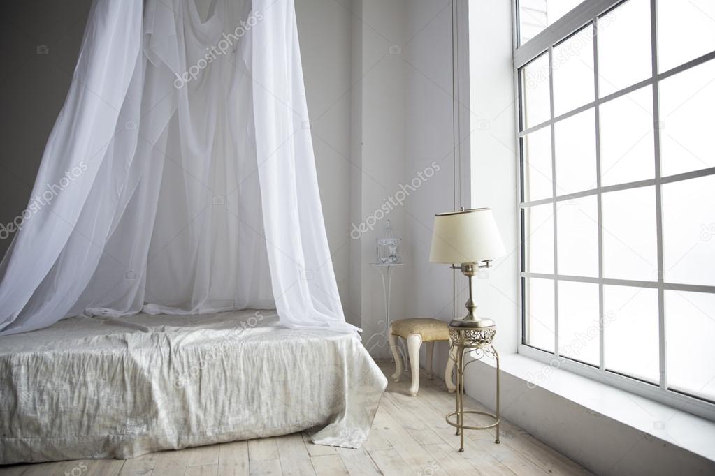 a cozy bedroom in pastel colors with a large bed, a table lamp o