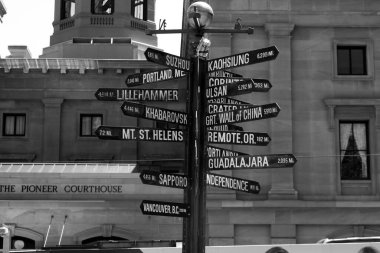 Sokak yolunun siyah beyaz görüntüsü farklı şehirlere yön ve mesafeleri gösteren oklarla şarkı söylüyor. 