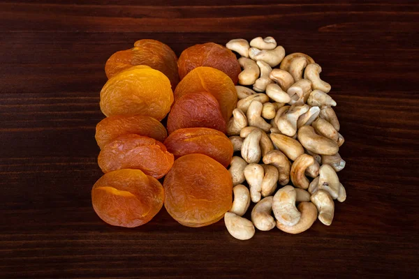 Cashew nuts and dried apricots on wooden table. Dried fruits and nuts concept — Stock Photo, Image