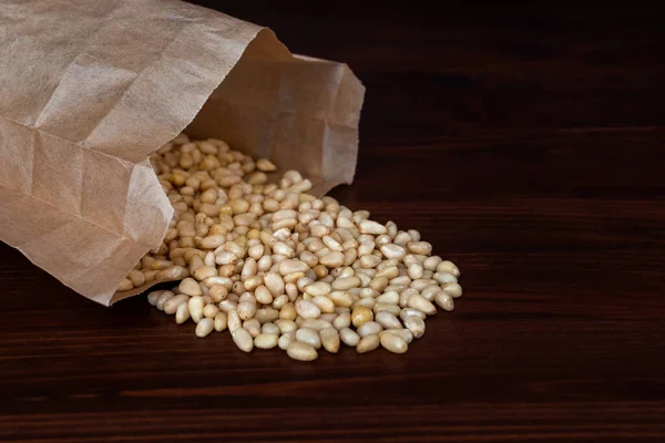 Bolsa de piñones sobre mesa de madera. Frutos secos dispersos — Foto de Stock