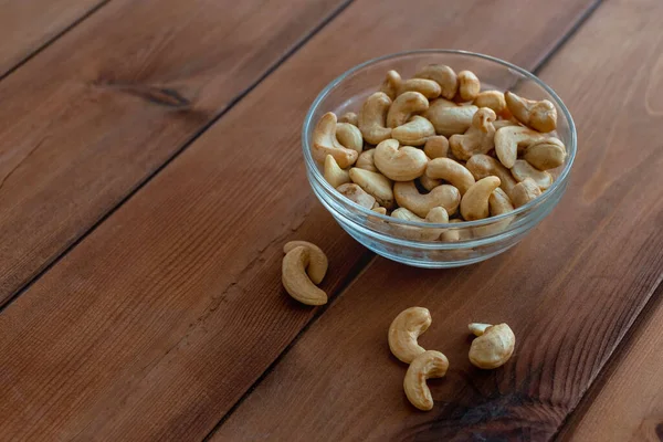 Bowl with roasted cashew nuts on wooden table — Stock Photo, Image