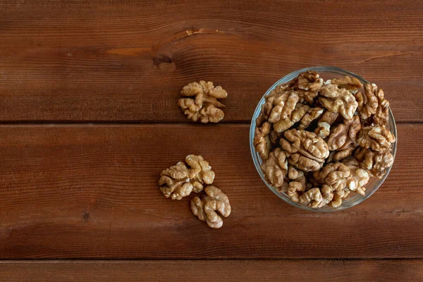 Walnuts in glass bowl on wooden table — Stock Photo, Image