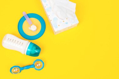 Bebek için beslenme aksesuarları. Bebek maması konsepti. Sütlü bebek şişesi, peçete, formüllü kaşık ve sarı arka planda armut.