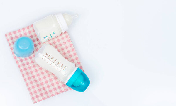 Feeding bottles of baby formula with powder and pacifier on white background. Bottles with blue caps