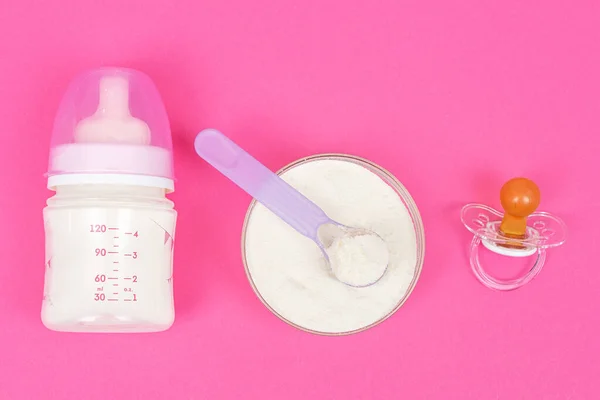Composition with feeding bottle of baby milk formula on pink background. Baby food concept
