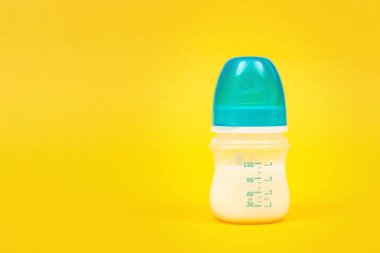 Sarı arka plan izolasyonunda bebek sütü şişesi. Yeni doğan için bir şişe süt.