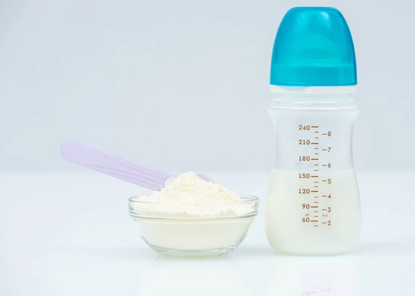 Powdered Milk, Baby Formula with spoon infant formula in bowl and bottle for feeding baby on white table. dairy food for baby