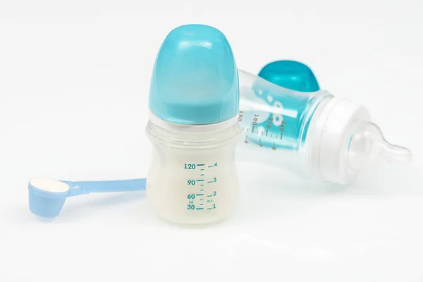 Feeding bottles and baby milk on white table. Baby bottles with scale