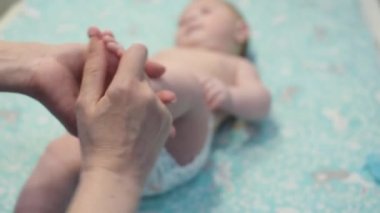 Anne bebeği için ayak masajı yapar. Küçük bebeğin ayağına masaj yapıyor. Yeni doğmuş bebeğin küçük ayaklarına yakın.