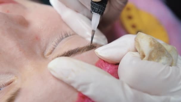 一种特殊的刺绣机对一个年轻姑娘的眉毛进行了永久性的化妆矫正 在皮肤下面注射深色色素 粉末喷涂特写 — 图库视频影像
