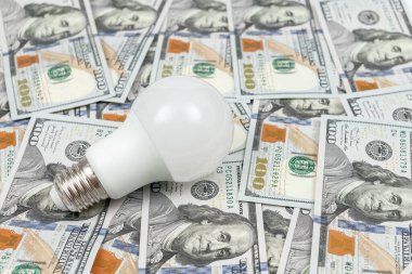 Energy Efficient Light Bulb on money background. Energy saving concept. White energy saving led lamp
