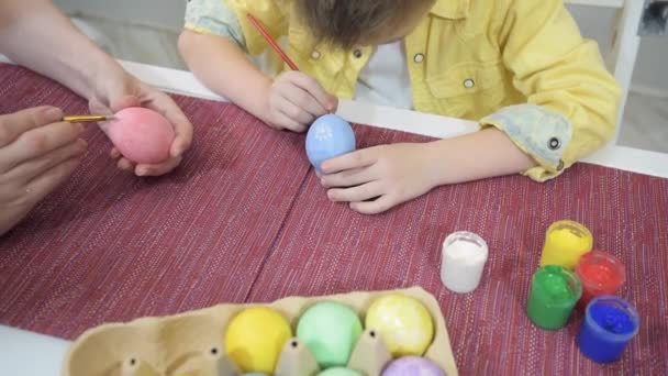 부활절을 준비하는 동안어린 어머니가 붓으로 달걀을 염색하기 위하여 페인트 가까이 — 비디오