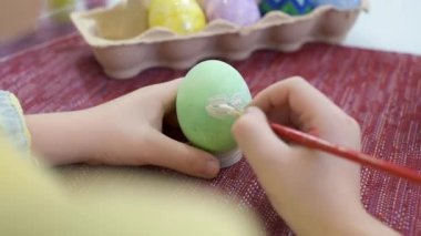 Paskalya yumurtalarını boyayan yaratıcı beyaz çocuk. Anaokulundaki çocuk paskalya şablonlarını beyaz boyayla çiziyor. Paskalya bayramı için hazırlık. Görüntüyü kapat