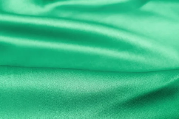 Abstraktní hladké elegantní zelené tkaniny textury pozadí. Vlnité záhyby hrubé hedvábné textury — Stock fotografie
