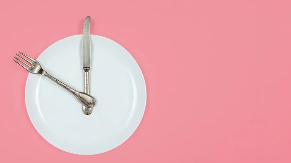 Concept de jeûne intermittent, l'heure du déjeuner, l'alimentation et la perte de poids. Grande assiette blanche et couverts sur fond rose pastel avec espace de copie — Photo